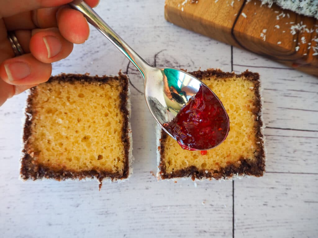 Lamingtons 34 Spooning jam onto cut open lamington
