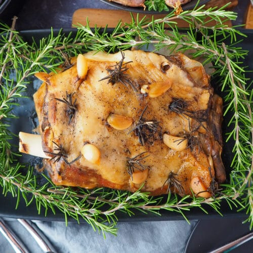 Slow cooker lamb shoulder 8 Close up slow cooker lamb roast on a serving plate, garnished with fresh rosemary.