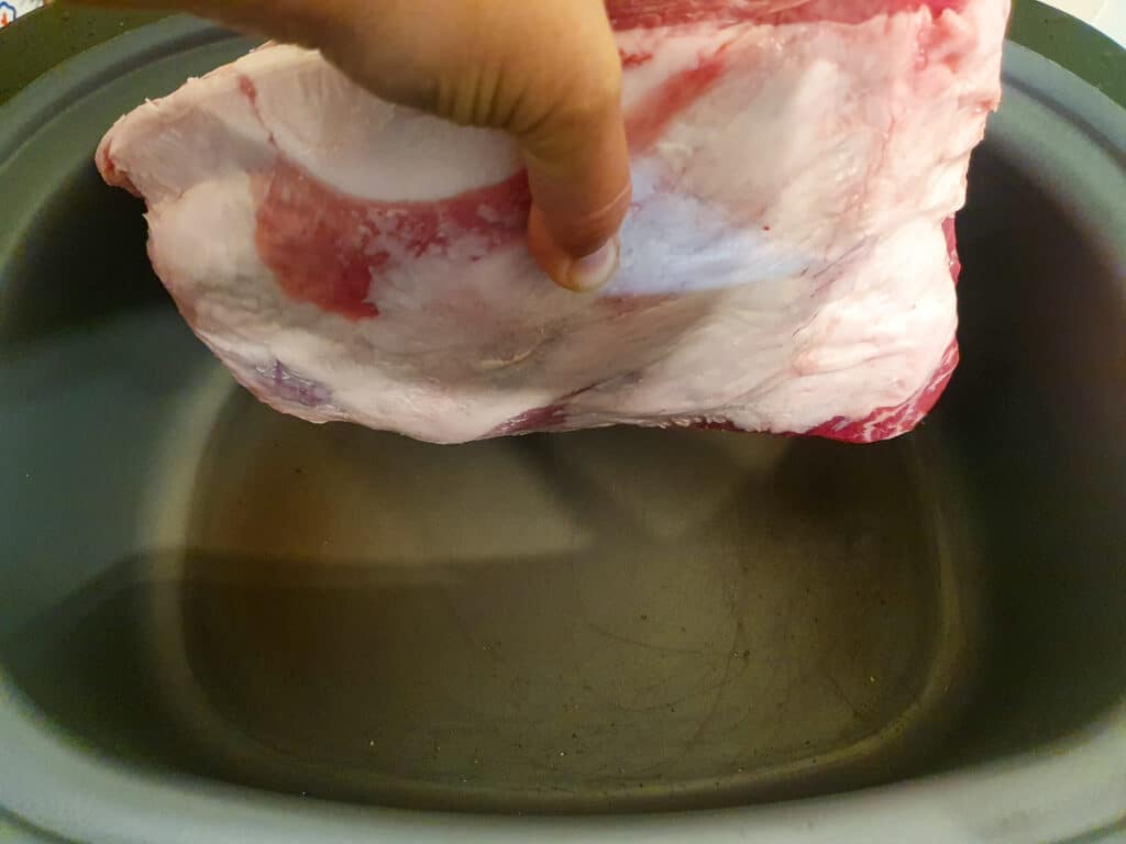 Slow cooker lamb shoulder 5 Putting the lamb into the heated searing slow cooker, fat side down.