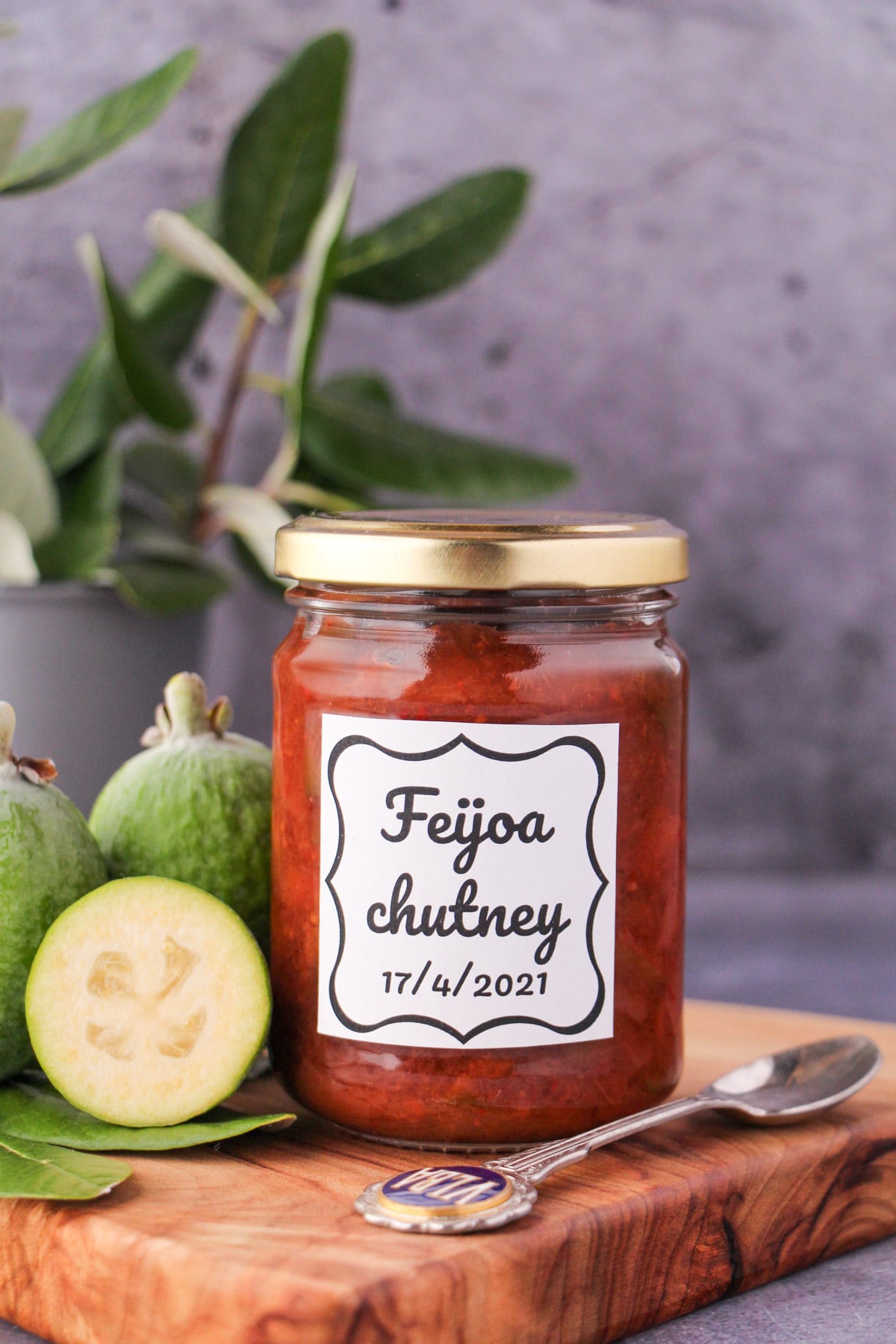 Feijoa chutney 20 Jar of homemade feijoa chutney on a board, with vintage spoon and fresh feijoas, and fresh feijoa leaves in the background.