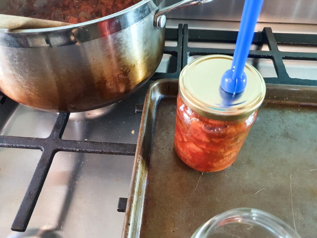 Feijoa chutney 15 Putting sterilized lid onto filled jars.