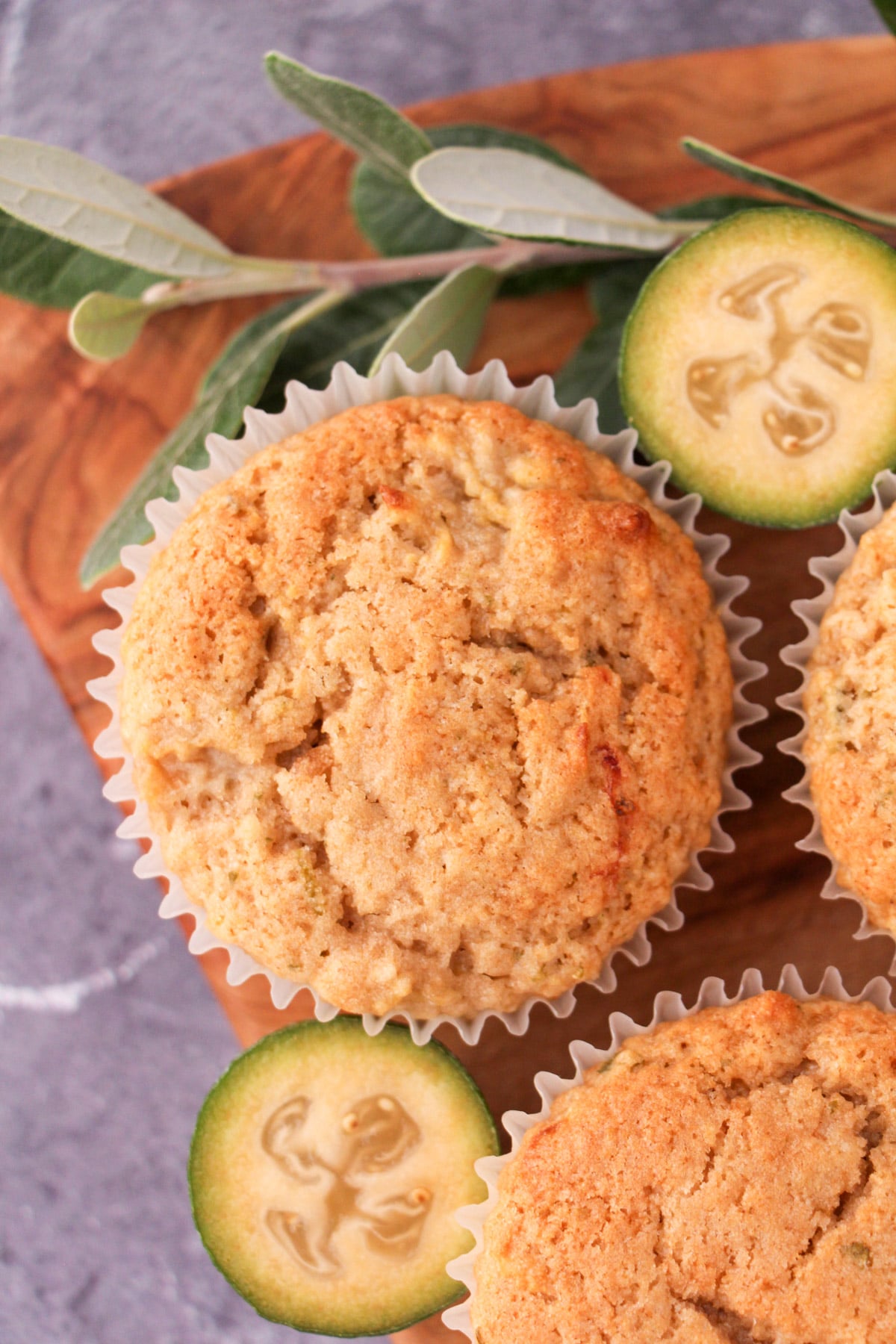Feijoa muffins 19 Feijoa muffins on a board with fresh feijoas and feijoa leaves.