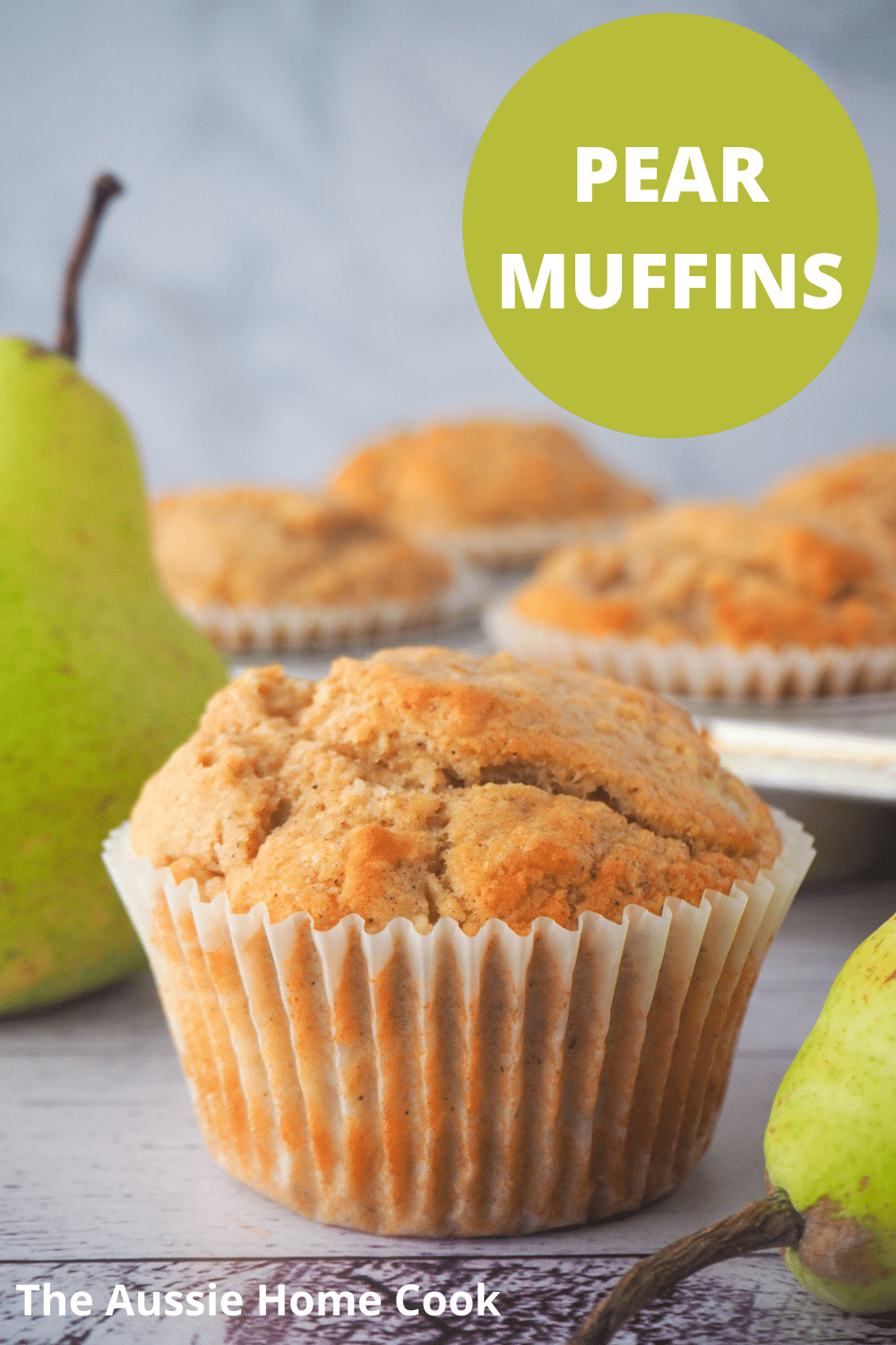 Pear muffins 16 Pear muffin with fresh pears and tray of muffins in the background, and text overlay, pear muffins, the aussie home cook..