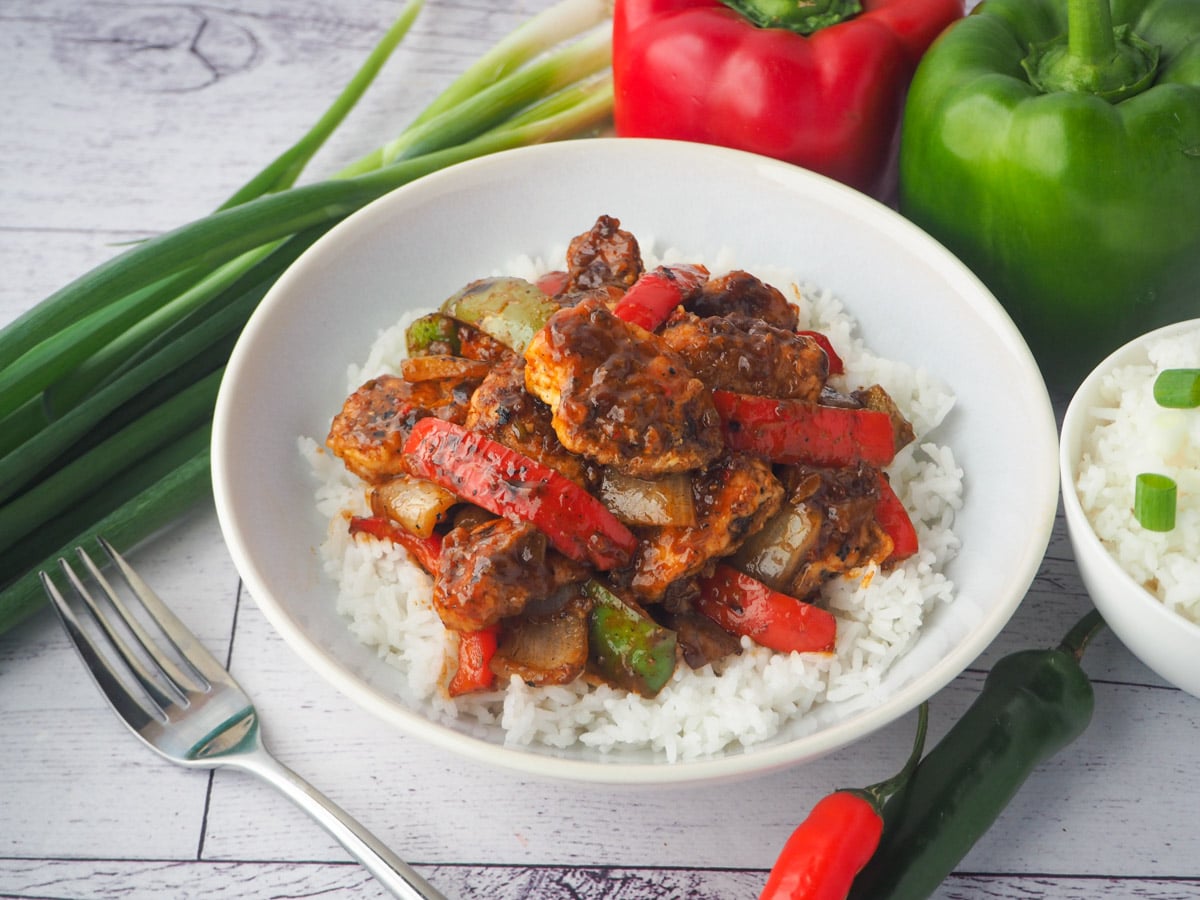 Chilli Chicken Gravy 23 Bowl of chicken on rice with fork, bowl of rice, capsicums, spring onions and chilli on the side.