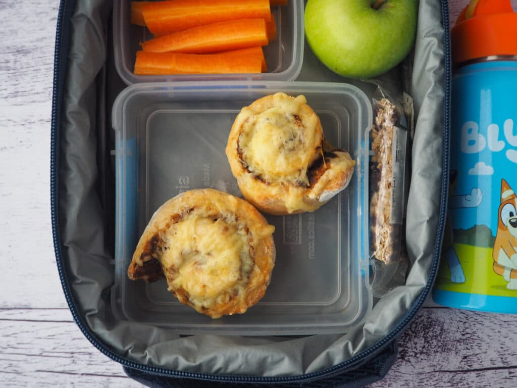 Cheesymite Scrolls 15 Scrolls in a lunchbox with carrot sticks, apple, muslie bar and drink bottle.
