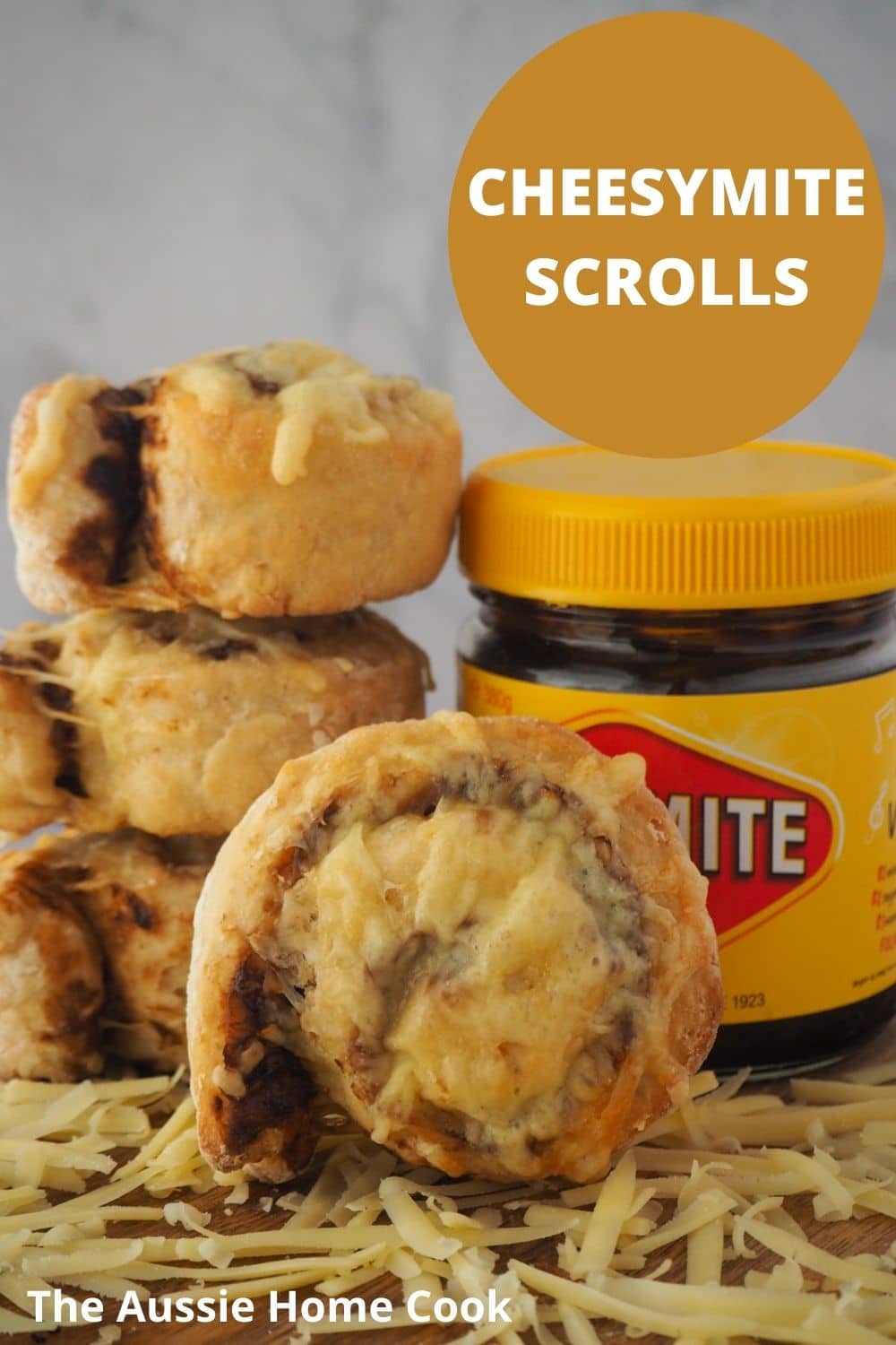 Cheesymite Scrolls 17 Scroll with stack of scrolls and jar of vegemite at the back, grated cheese and the front and text overlay, cheesymite scrolls and The Aussie Home Cook.