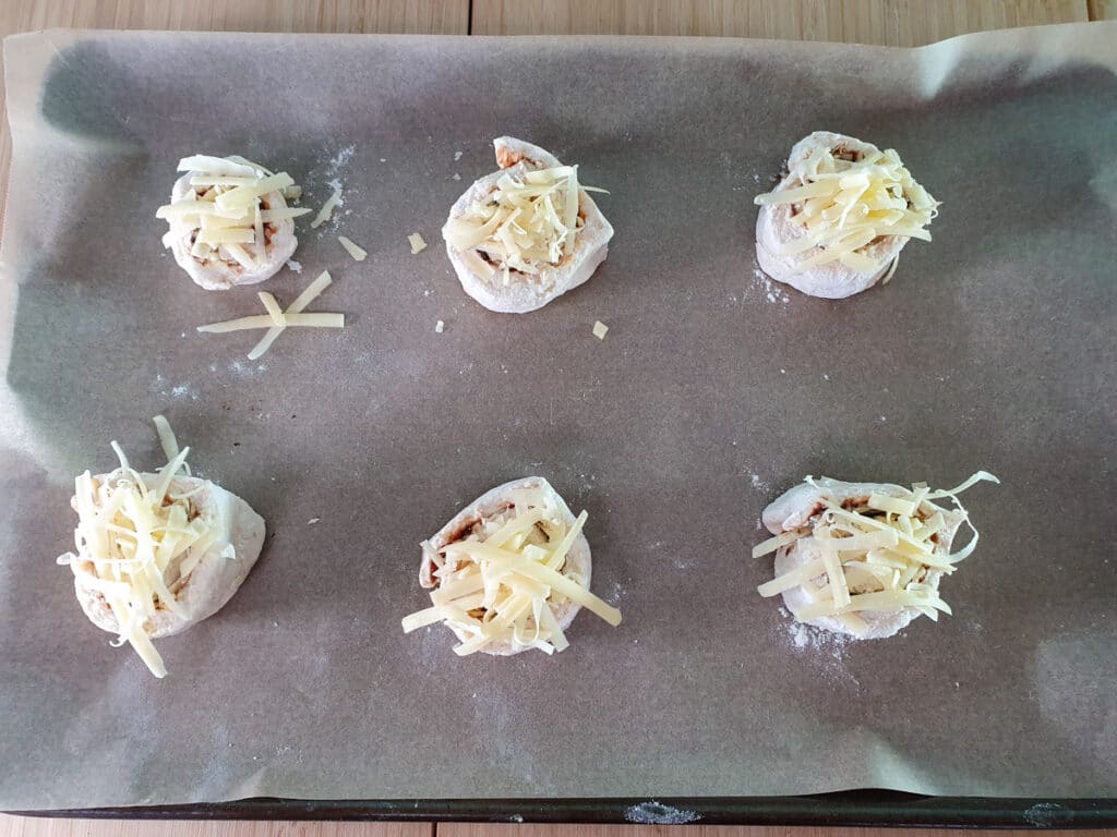 Cheesymite Scrolls 13 Ready to bake scrolls, scroll side up, with cheese sprinkled on top.