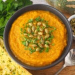 Pumpkin and Sweet Potato Soup 20 Close up soup with pumpkin seeds and parsley garnish.