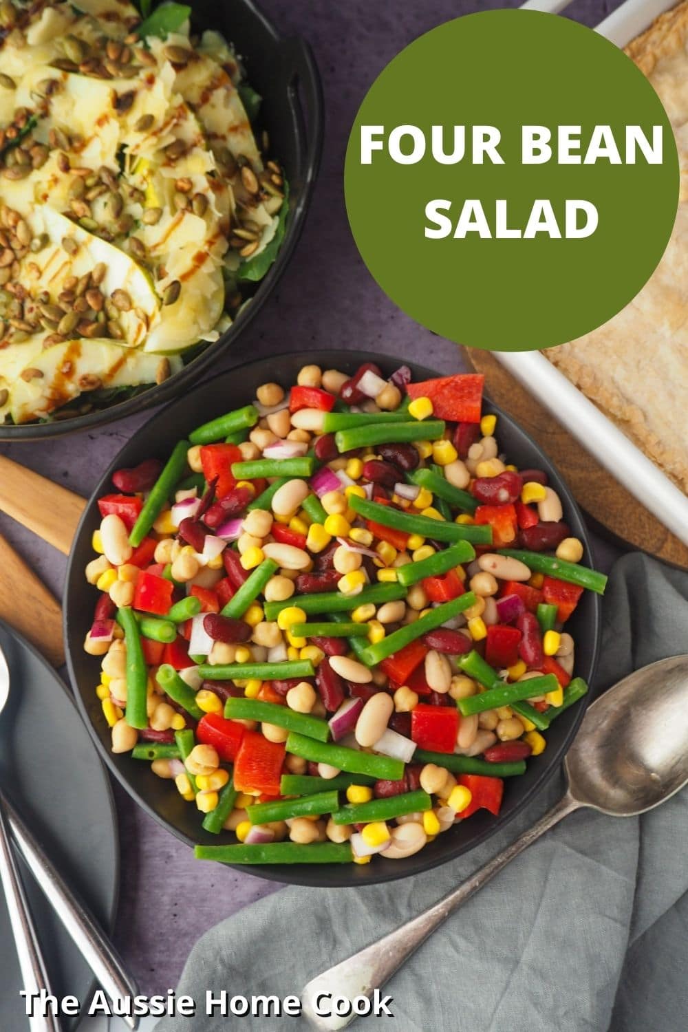 Four Bean Salad 15 Bowl of salad with serving spoon, with pie and another salad on the side, with text overlay, Four Bean Salad and The Aussie Home Cook.