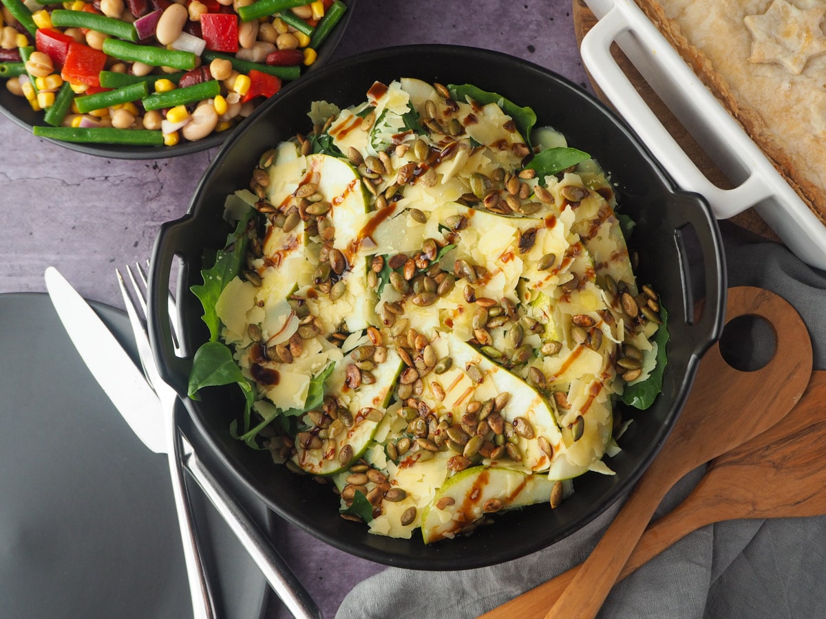 Rocket and Pear Salad 1 Salad with serving spoons, plate, knife and fork, pie and four bean salad in the background.