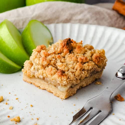 Apple Slice 28 Close up piece of apple slice on a plate with a fork and fresh apple on the side.