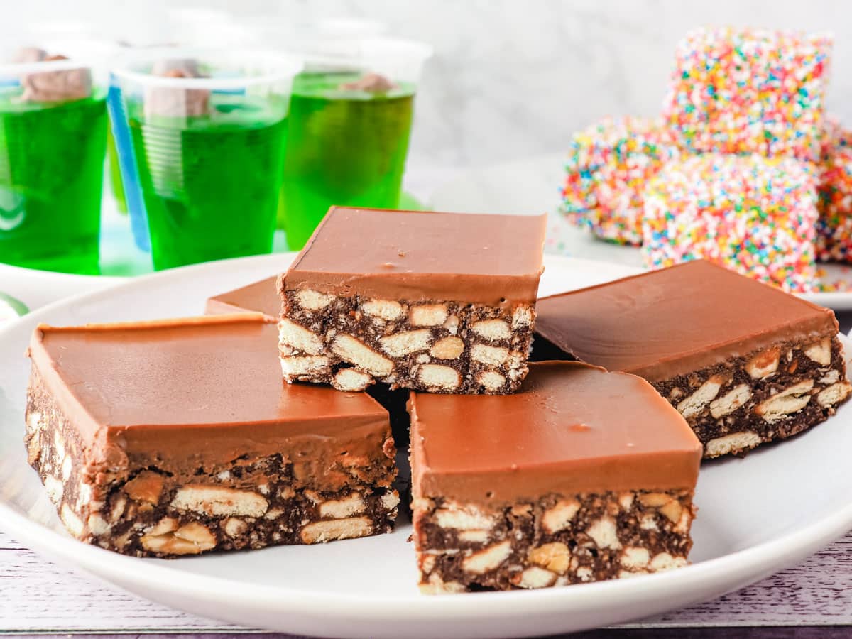 Hedgehog Slice 7 Chocolate condensed milk slice on a serving plate with party food in the background.